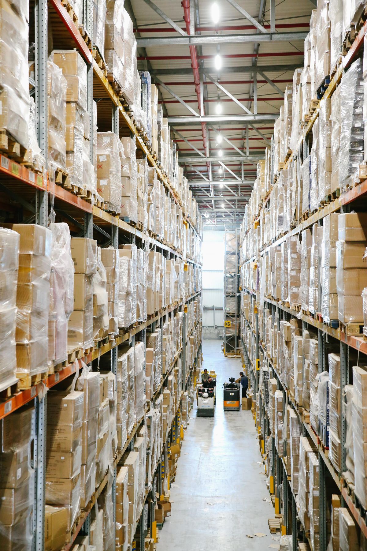 Tall warehouse aisle lined with shelves of stacked boxes