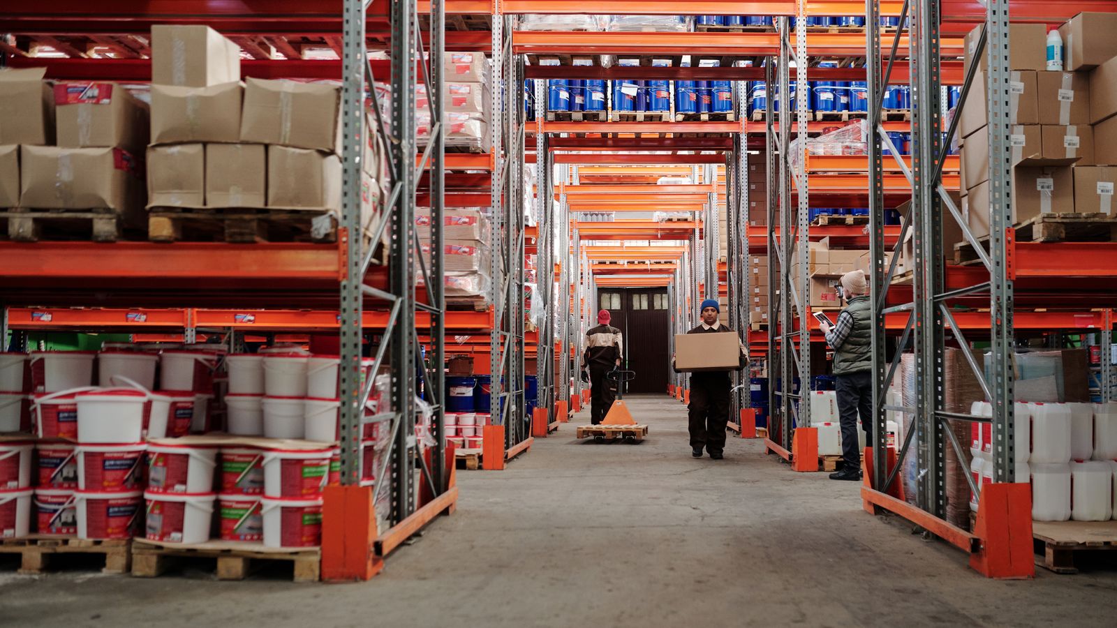 Warehouse workers handling boxes beside organized shelves