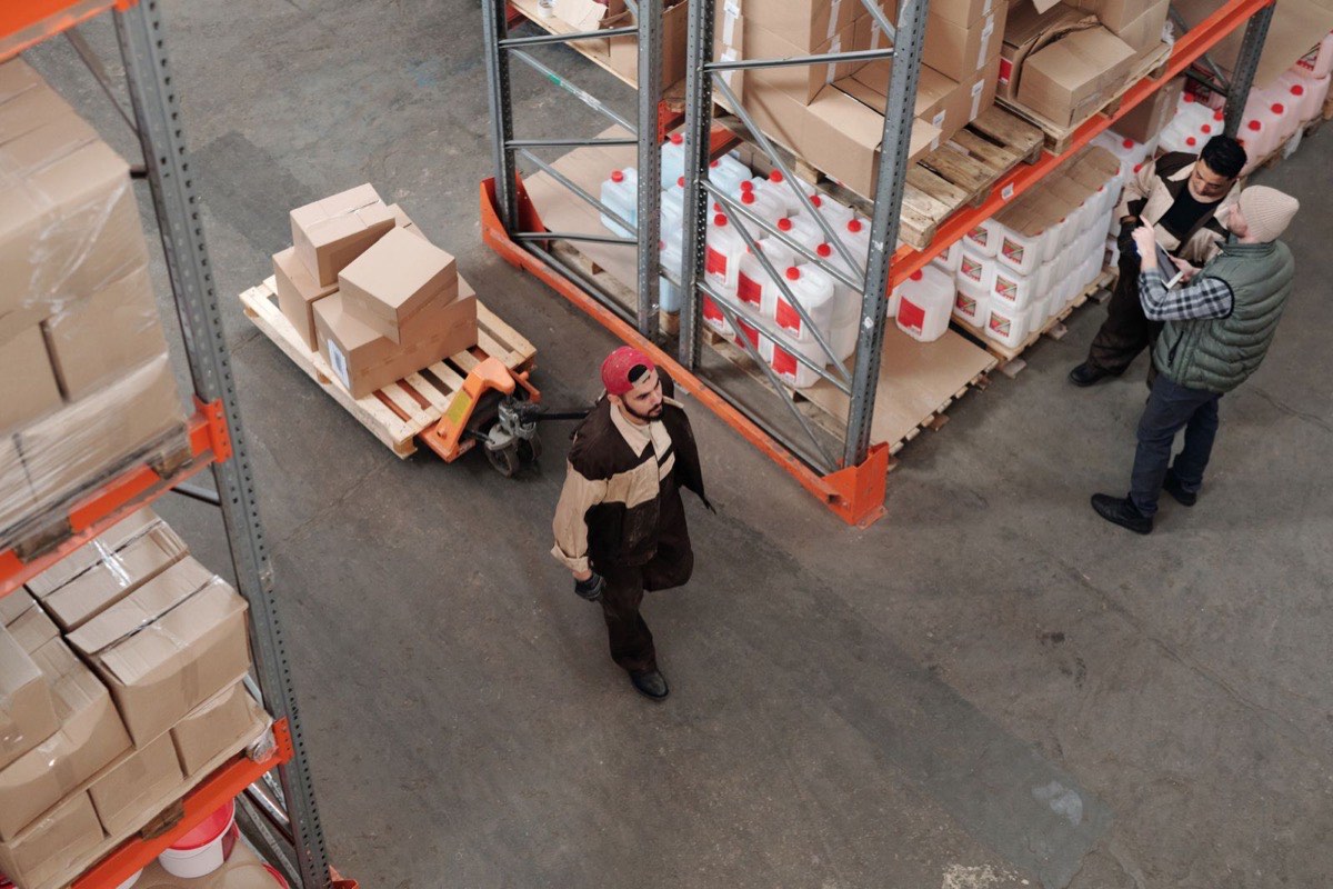 Overhead view of a warehouse with pallet racking, boxes, and staff reviewing inventory