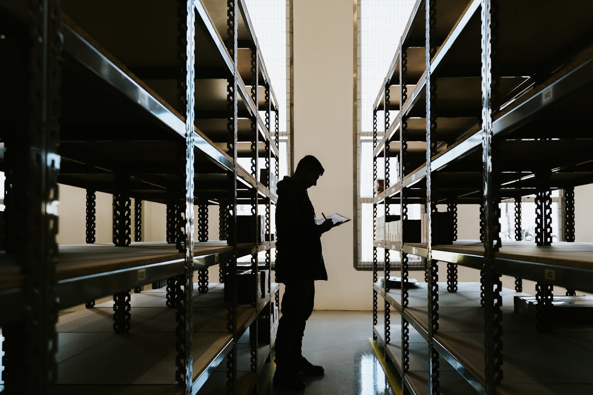 Silhouette of a person reviewing inventory between warehouse racks