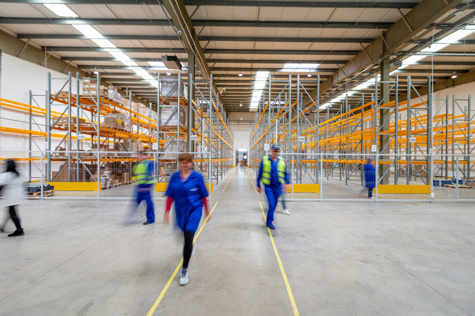 Warehouse worker walking down an aisle between tall storage shelves