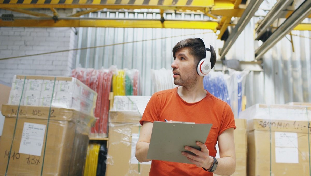 Warehouse worker holding a clipboard beside incoming cartons