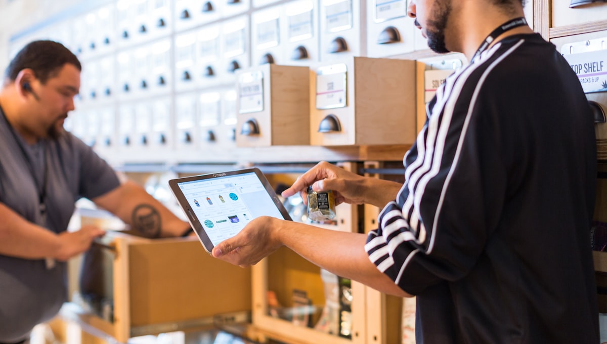Warehouse worker reviewing inventory on a tablet beside shelving
